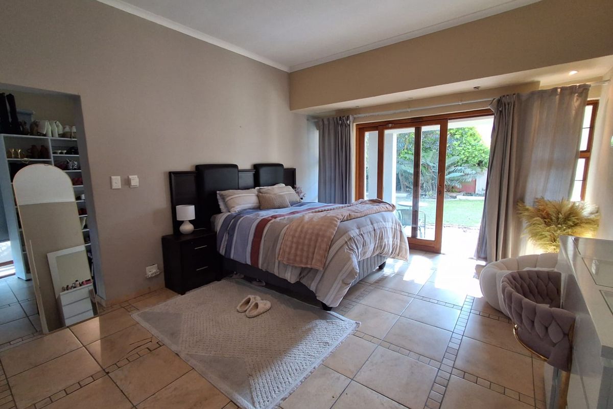 Spacious bedroom featuring tiled flooring, a walk-in closet area, and large sliding glass doors providing direct access to the rear garden.