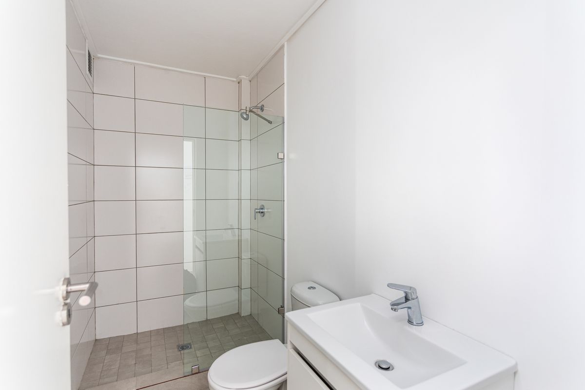 A modern, clean bathroom featuring a glass-enclosed walk-in shower, a white vanity with a basin, and a toilet.