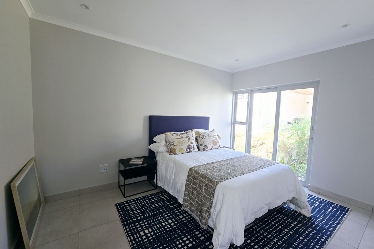 A bright bedroom featuring neutral walls, tiled flooring, recessed lighting, and a sliding glass door providing direct access to the outdoor area.
