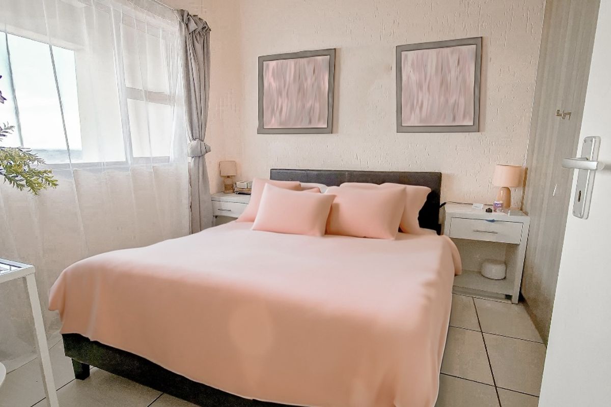 A cozy bedroom featuring tiled flooring, textured wall finishes, and a large window allowing for natural light.