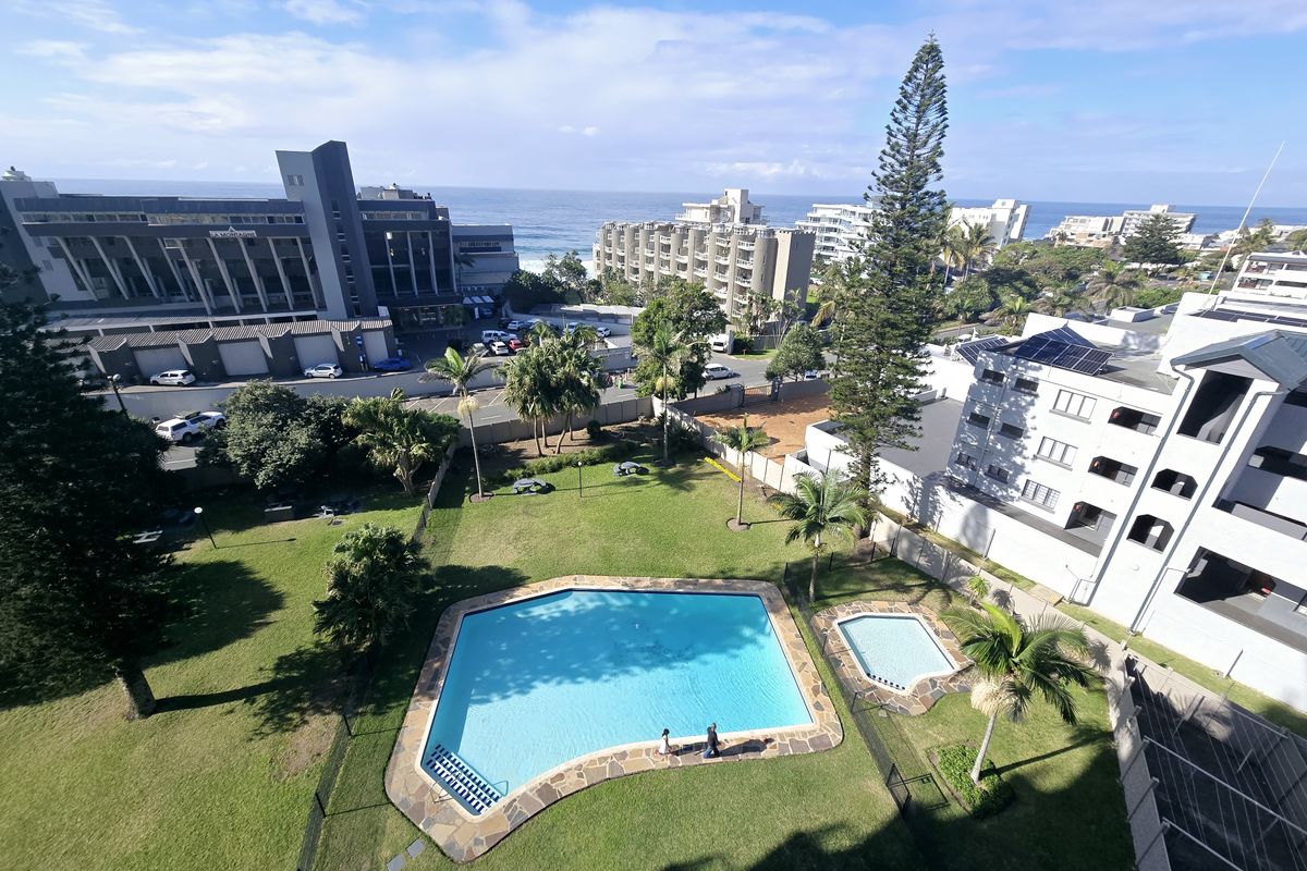 Aerial view of the apartment complex grounds featuring a well-maintained swimming pool, wading pool, and landscaped garden area with surrounding residential buildings.