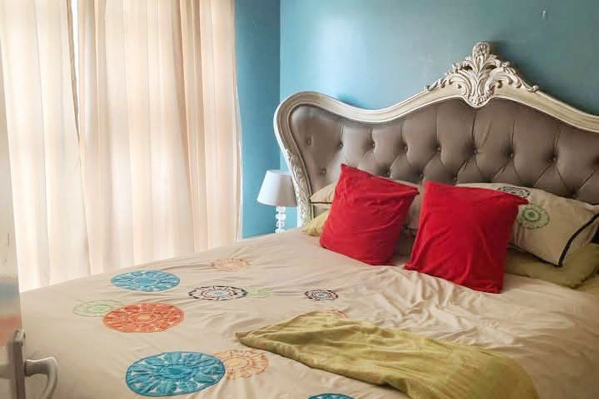 A bedroom featuring blue painted walls and a window with curtain fixtures.