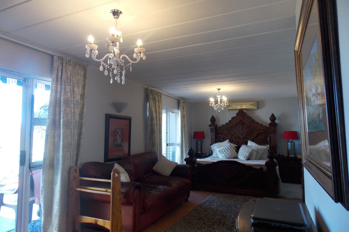 Spacious bedroom featuring a built-in air conditioning unit, tiled flooring, and direct access to an outdoor patio area through sliding glass doors.