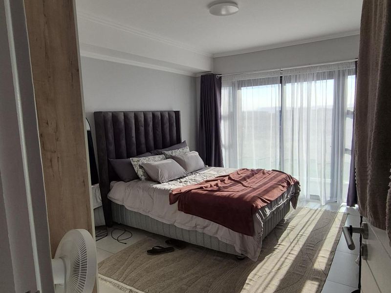 A bright and modern bedroom featuring large sliding glass doors that provide ample natural light and access to an outdoor area.