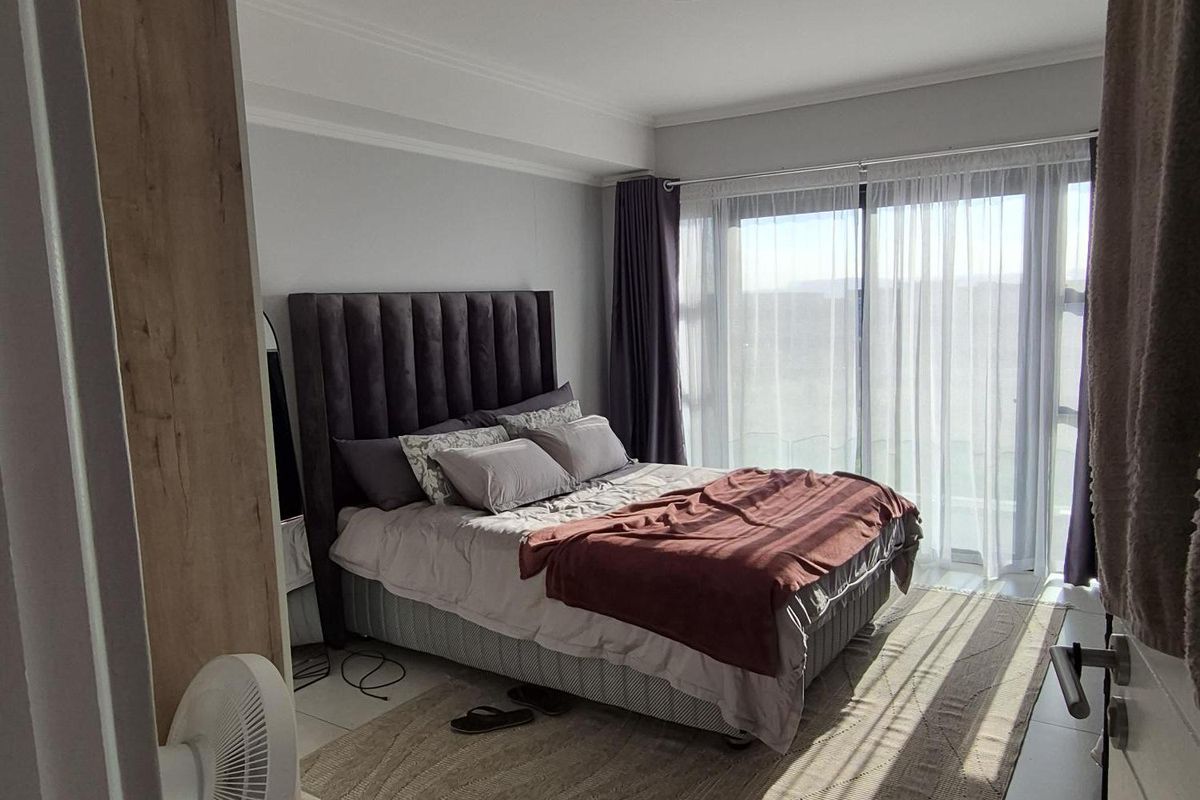 A bright and modern bedroom featuring large sliding glass doors that provide ample natural light and access to an outdoor area.