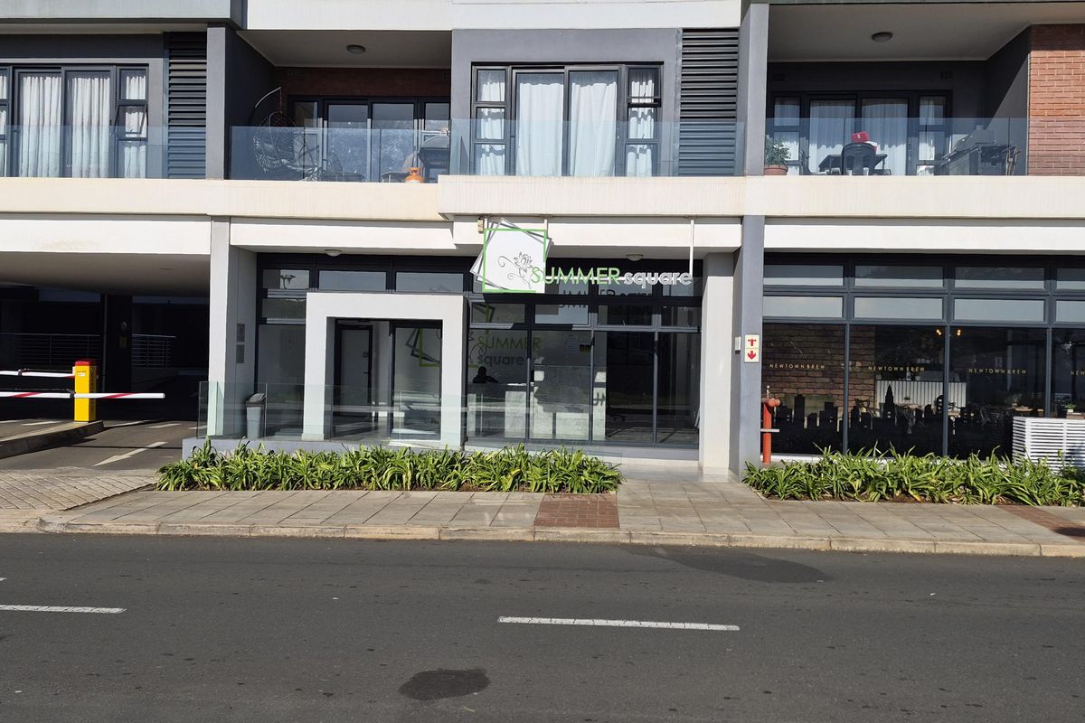 Street-level view of the Summer Square apartment complex entrance, featuring modern glass facade, balcony railings, and paved pedestrian access.