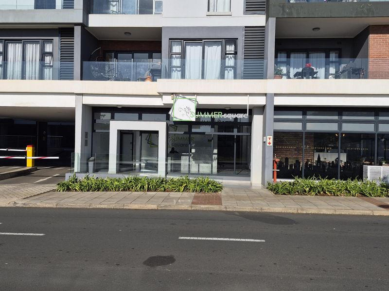 Street-level view of the Summer Square apartment complex entrance, featuring modern glass facade, balcony railings, and paved pedestrian access.