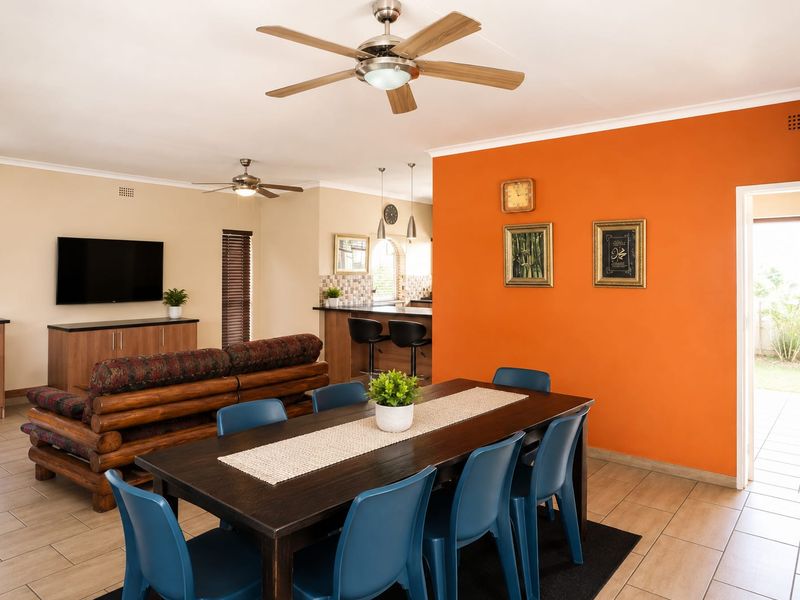 Open-plan living and dining area featuring tiled floors, ceiling fans, and a breakfast bar connecting to the kitchen space.