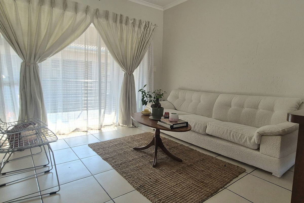 A bright living room featuring tiled flooring and large sliding glass doors that provide access to an outdoor area.