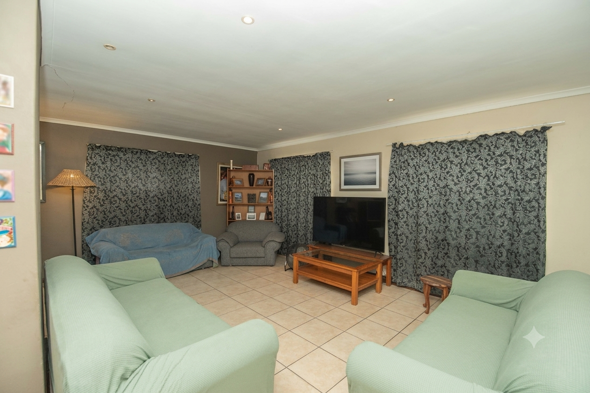 A spacious living room featuring tiled flooring and recessed ceiling lighting, providing a functional and comfortable area for relaxation.