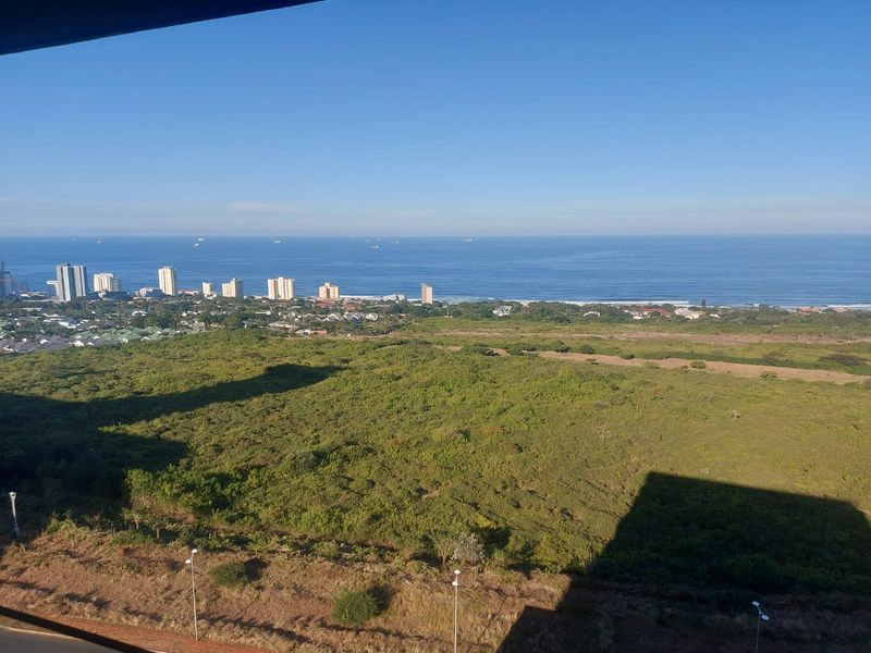 Expansive elevated coastal view overlooking natural green space and the distant ocean horizon.