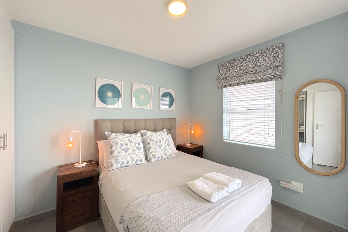 A well-maintained bedroom featuring neutral tiled flooring, built-in cabinetry, and a window with fitted blinds, offering a clean and comfortable living space.