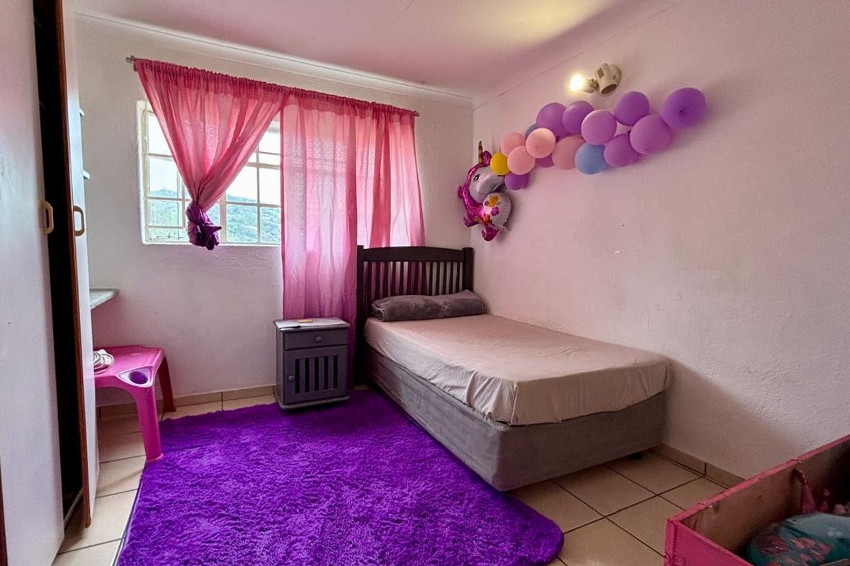 A bedroom featuring tiled flooring, built-in wardrobe storage, and a window with natural light.