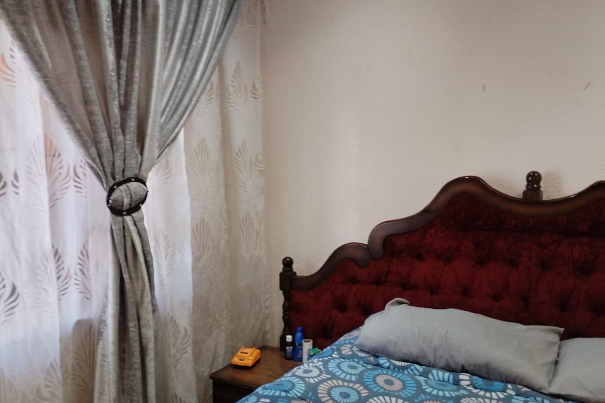 A cozy bedroom featuring a window with decorative curtains and recessed ceiling lighting.