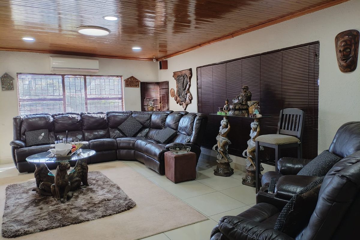 Spacious living room featuring a polished timber-paneled ceiling, tiled flooring, and a wall-mounted air conditioning unit.