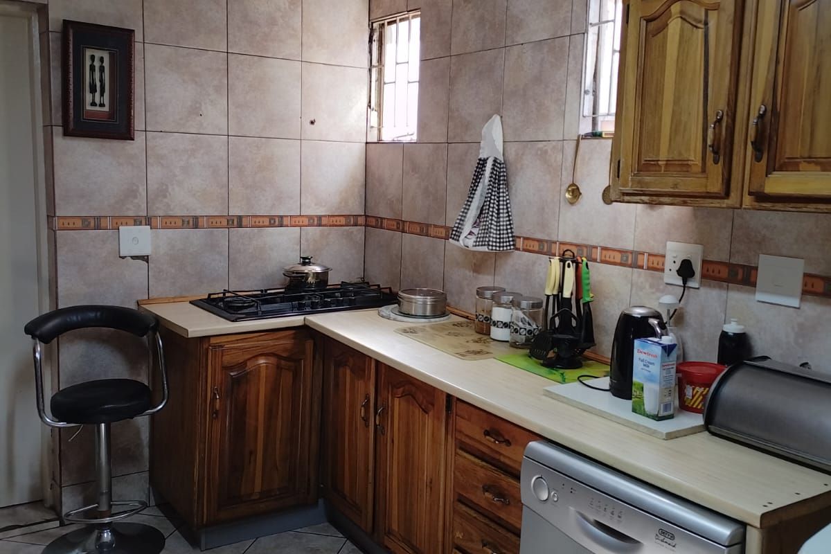 A functional kitchen featuring wooden cabinetry, tiled walls, a built-in gas hob, and space for a dishwasher.