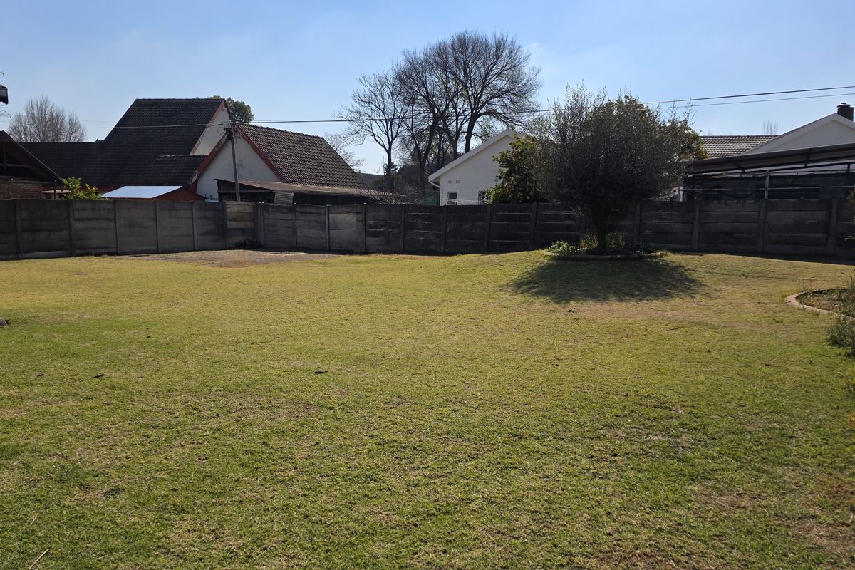 A spacious rear garden featuring a large lawn area enclosed by a precast concrete boundary wall.