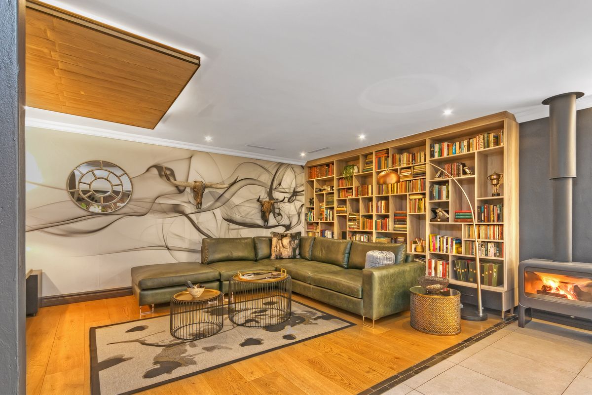 A well-appointed living room featuring custom floor-to-ceiling wooden bookshelves, a modern freestanding fireplace, and high-quality timber flooring.