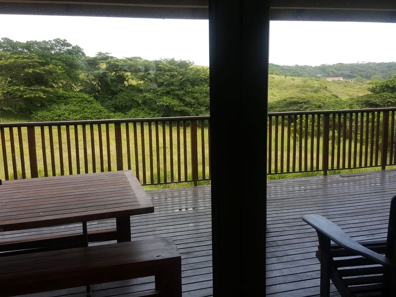 A covered timber deck featuring a wooden balustrade, offering expansive views of the surrounding natural landscape.