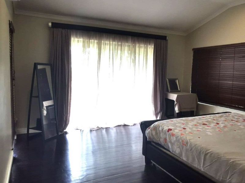 Spacious bedroom featuring dark hardwood flooring, recessed lighting, and a wall-mounted air conditioning unit with large sliding doors leading to the exterior.