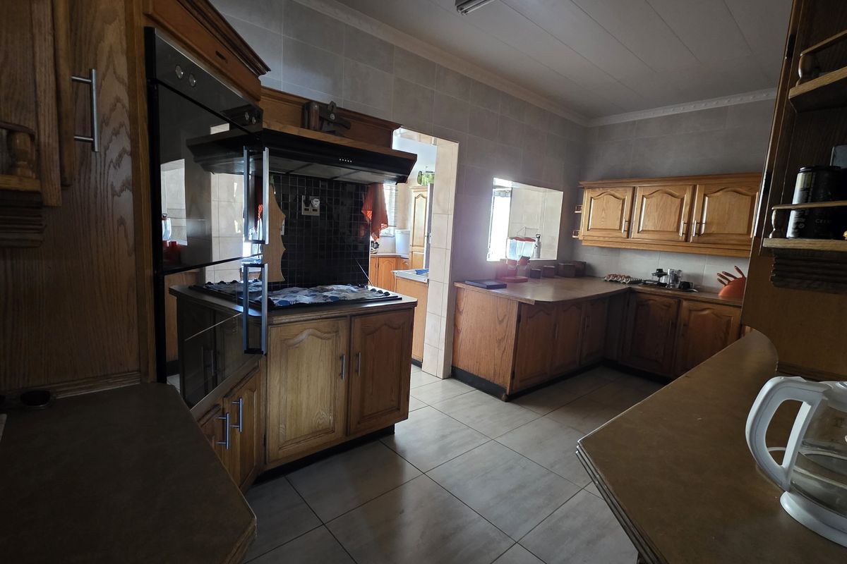 A functional kitchen featuring traditional wooden cabinetry, built-in oven, hob, and tiled flooring, offering a classic layout with potential for modern updates.