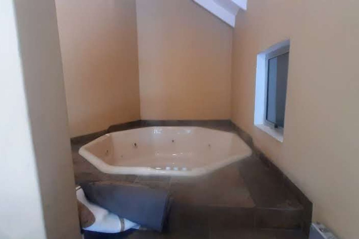A bathroom featuring a built-in corner spa bathtub with tiled surround and neutral wall finishes.