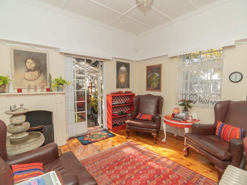 A cozy living room featuring original timber flooring, a classic fireplace with mantelpiece, and high coved ceilings, offering a warm and traditional atmosphere.