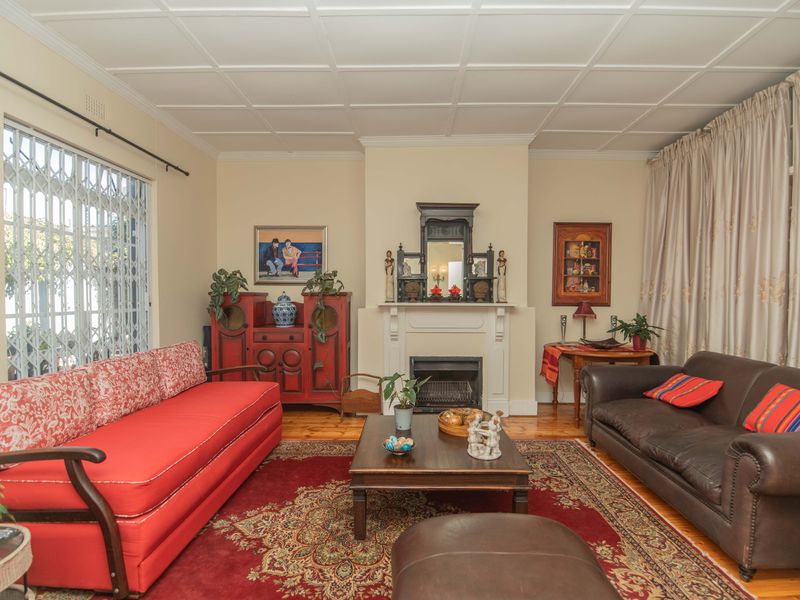 A traditional living room featuring timber flooring, a central fireplace with a mantelpiece, and a decorative coffered ceiling.