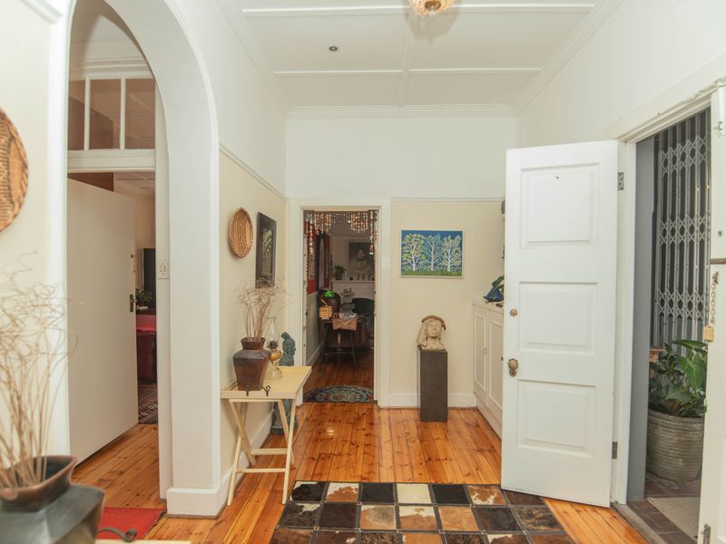 A bright hallway featuring polished timber flooring, classic archway detailing, and traditional panelled doors leading to adjacent living spaces.