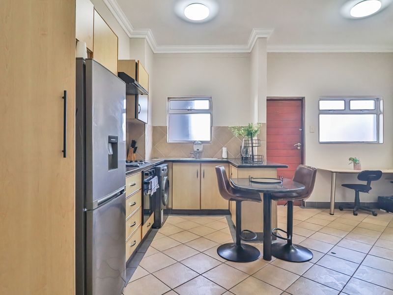 Functional kitchen featuring laminate cabinetry, granite countertops, built-in oven, hob, and tiled flooring, with an integrated breakfast nook area.