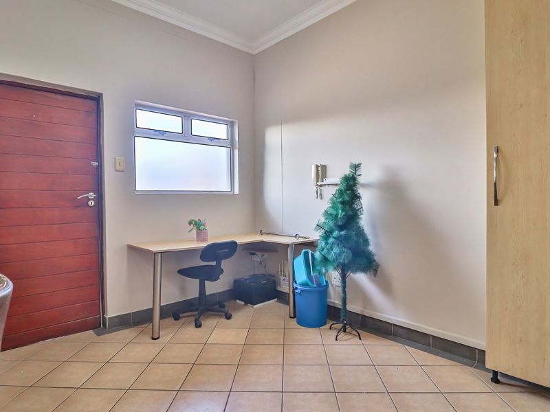 A functional office space featuring tiled flooring, a built-in cupboard, and an intercom system, providing a practical area for work or study.