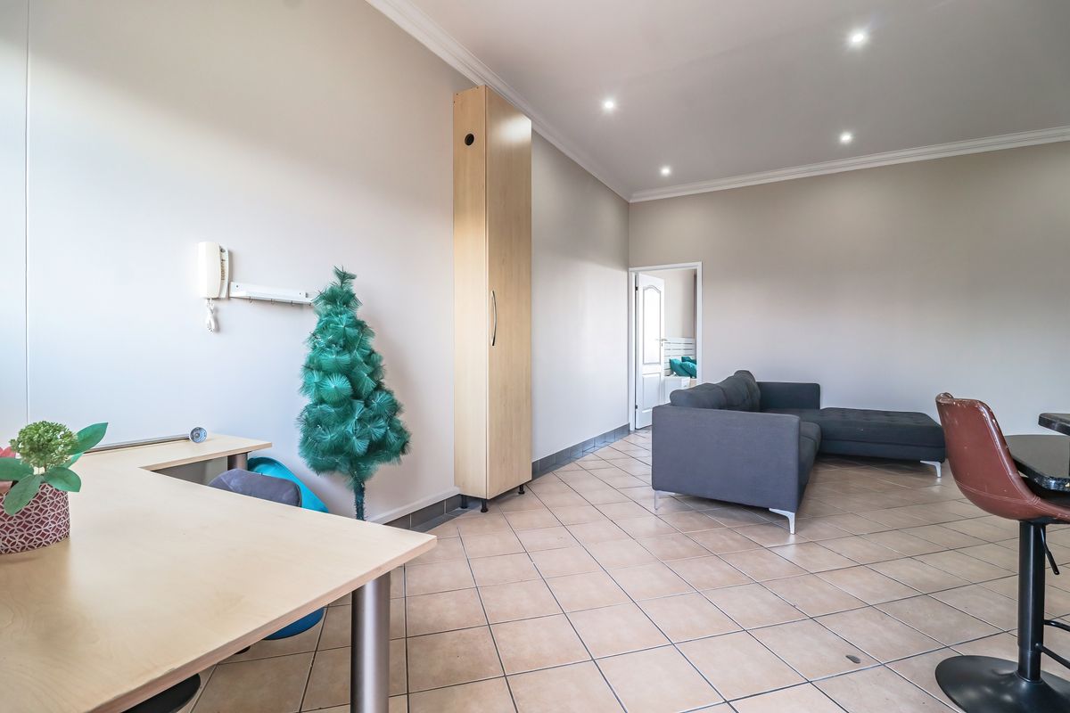 Spacious living area featuring tiled flooring, recessed downlighting, and a built-in storage cabinet, offering a versatile layout for comfortable living.
