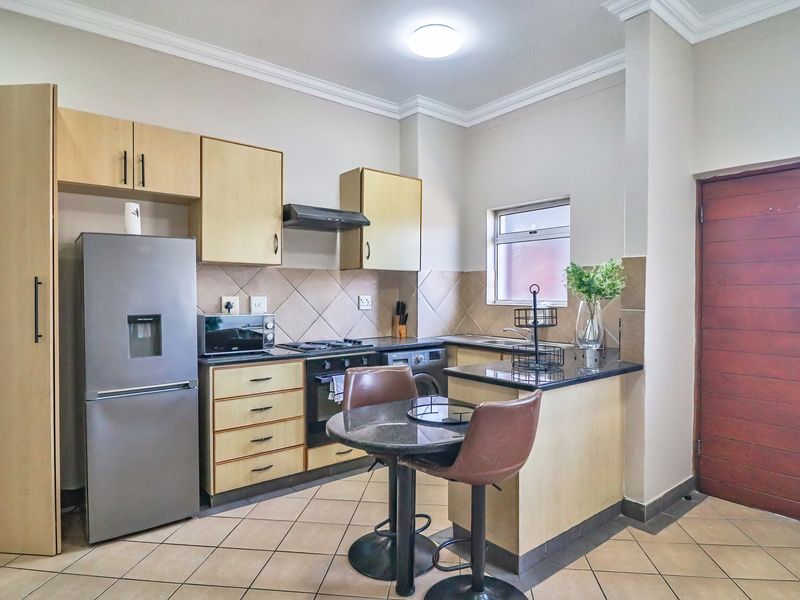 A functional kitchen featuring light wood cabinetry, granite countertops, a tiled backsplash, and integrated appliances, offering a practical layout for daily use.