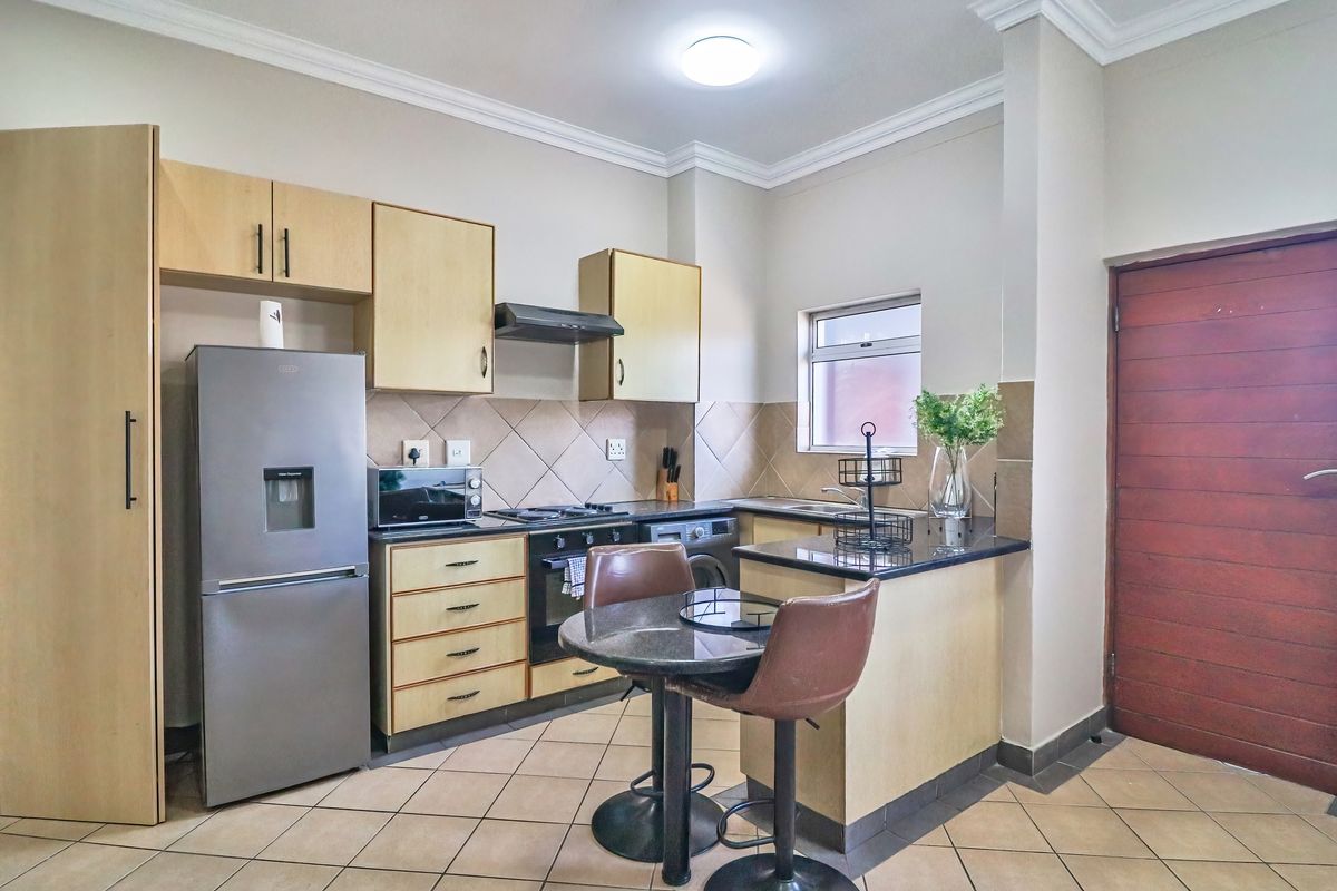 A functional kitchen featuring light wood cabinetry, granite countertops, a tiled backsplash, and integrated appliances, offering a practical layout for daily use.