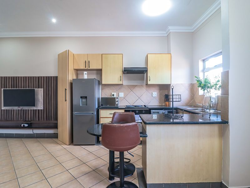 Open-plan kitchen and living area featuring light wood cabinetry, granite countertops, tiled flooring, and a breakfast nook, creating a functional and connected living space.