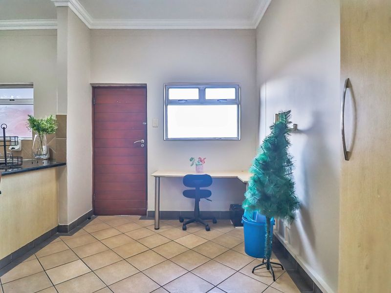 Open plan living area featuring tiled flooring, granite kitchen counter space, and direct access to a timber door.