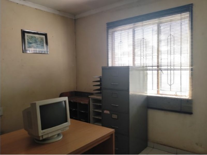 A functional office space featuring a window with fitted blinds and neutral wall finishes, suitable for a home workspace or study.
