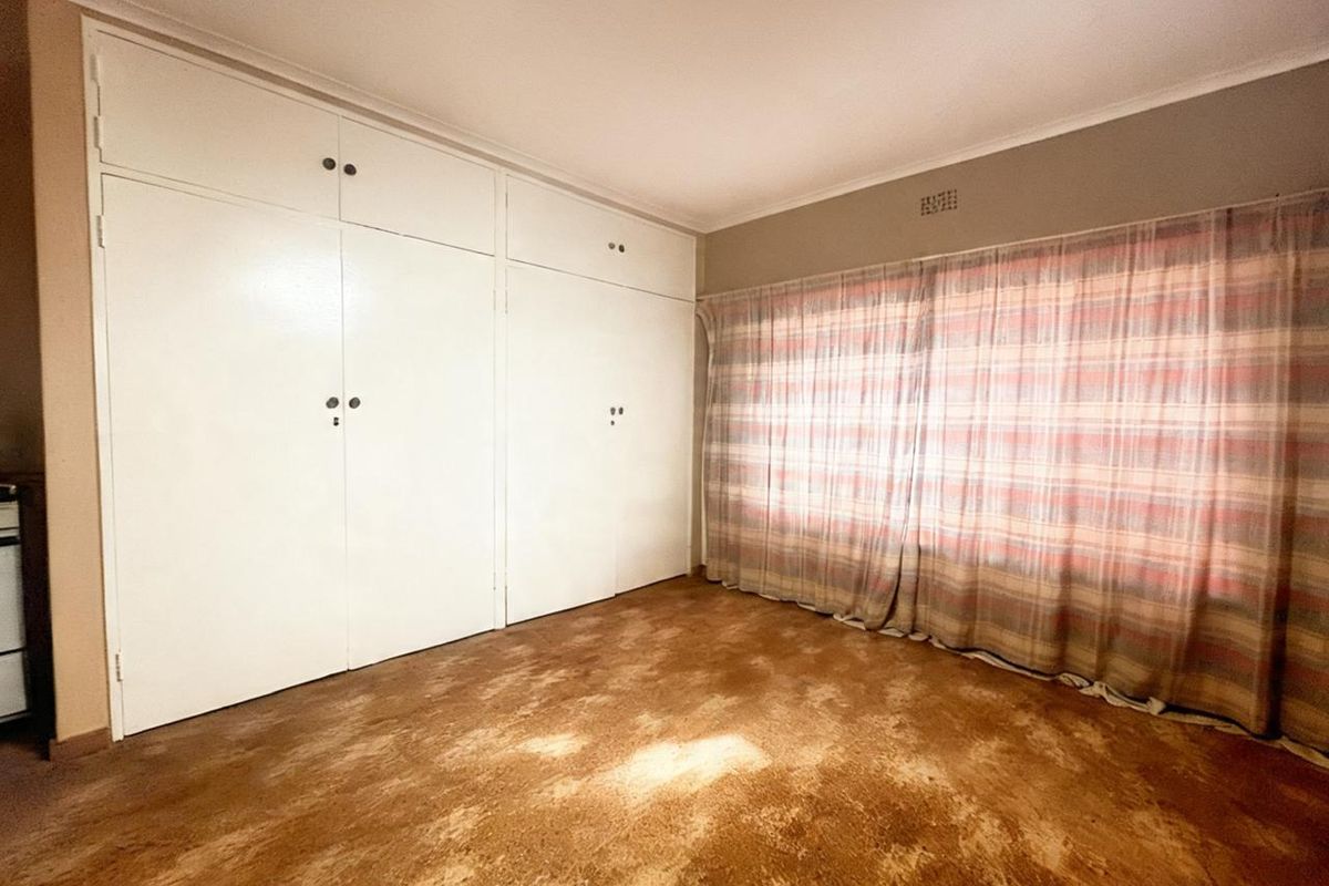 A vacant bedroom featuring built-in cupboards and carpet flooring, offering a blank canvas for renovation or interior design updates.