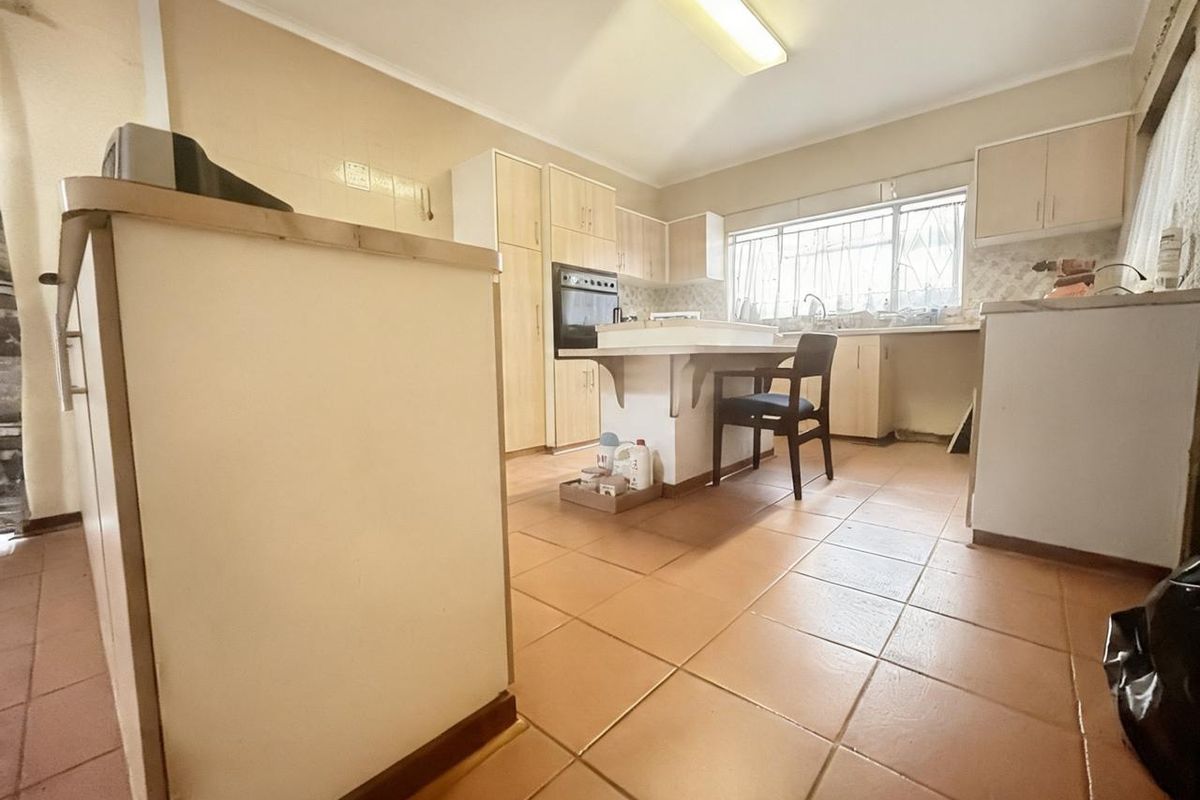A dated kitchen featuring tiled flooring, built-in cabinetry, a central island, and a built-in oven, offering significant potential for modernization and renovation.
