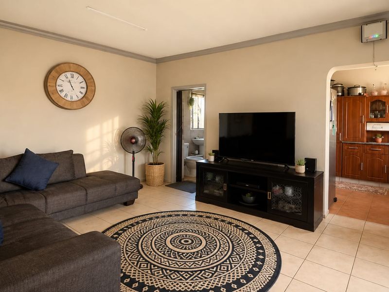 Open-plan living area featuring tiled floors and an arched transition to the kitchen, with a view into an adjacent bathroom.