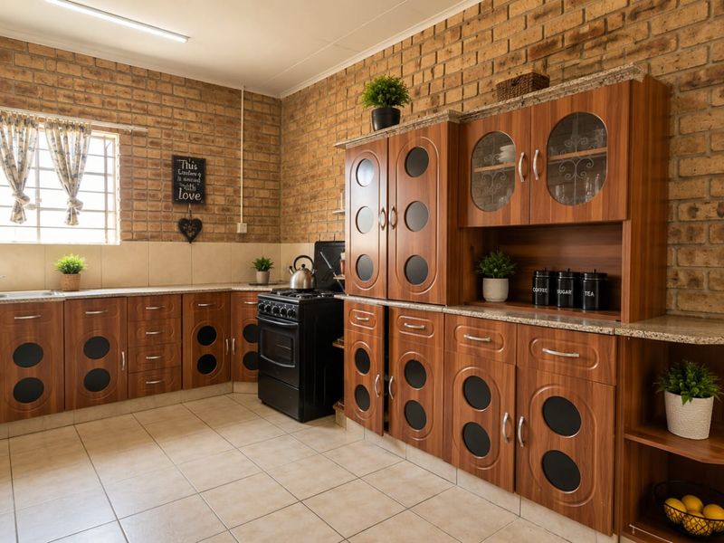 A functional kitchen featuring exposed brick walls, wood-finish cabinetry with circular glass accents, granite countertops, and tiled flooring.