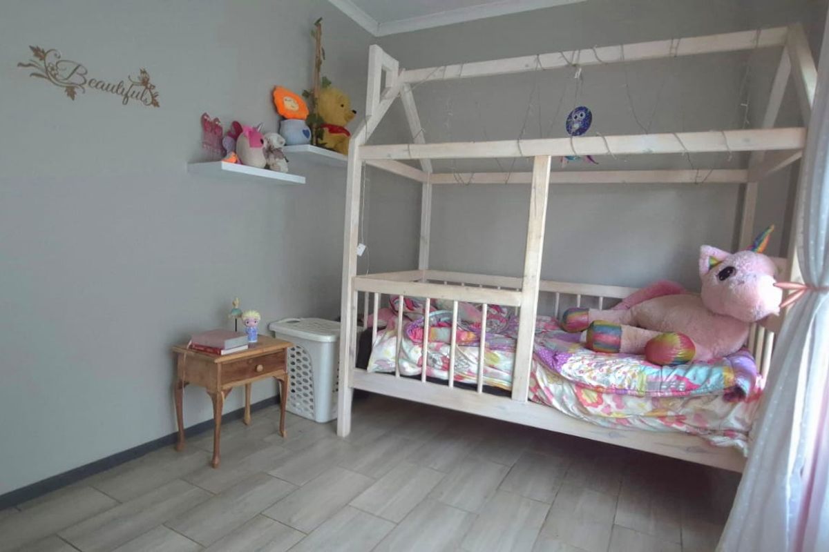 A bedroom featuring neutral grey walls and tiled flooring, providing a clean and functional space.