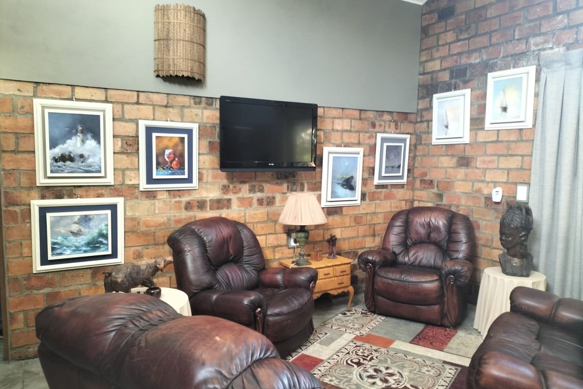A living room featuring a prominent exposed brick feature wall, high ceilings, and neutral painted upper wall sections.
