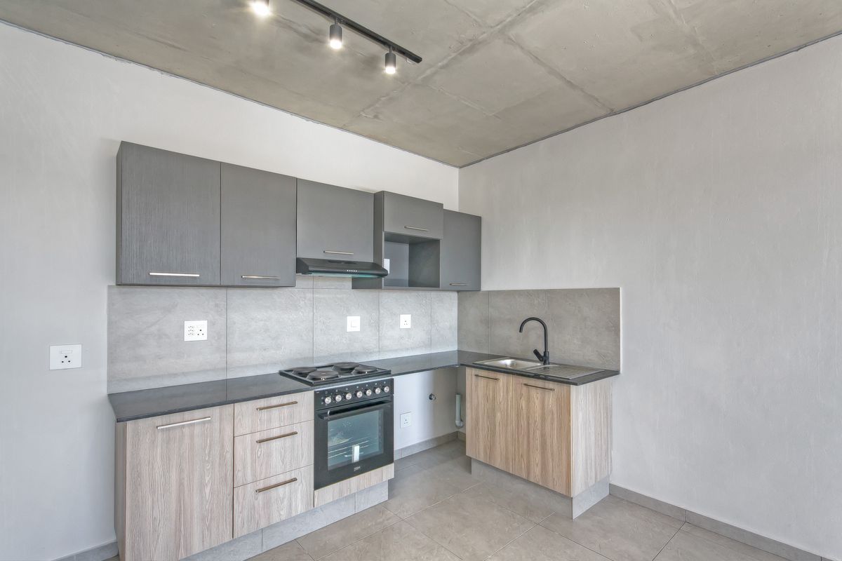 Modern kitchen featuring two-tone cabinetry, stone-look countertops, integrated oven and hob, and a sleek black faucet against a tiled backsplash.
