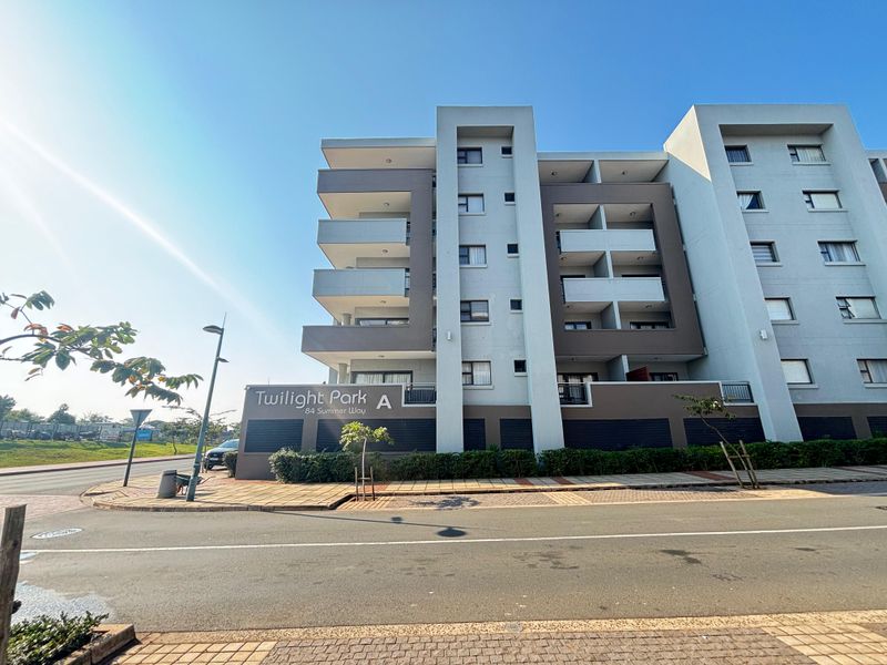 Exterior view of the Twilight Park apartment complex, showcasing the modern facade, balconies, and street-level entrance.