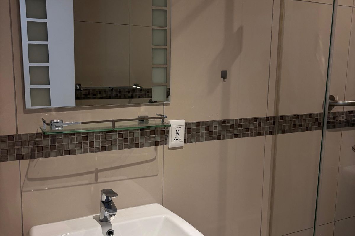 A modern bathroom featuring a pedestal basin, glass shower enclosure, and decorative mosaic tile accents on the wall.