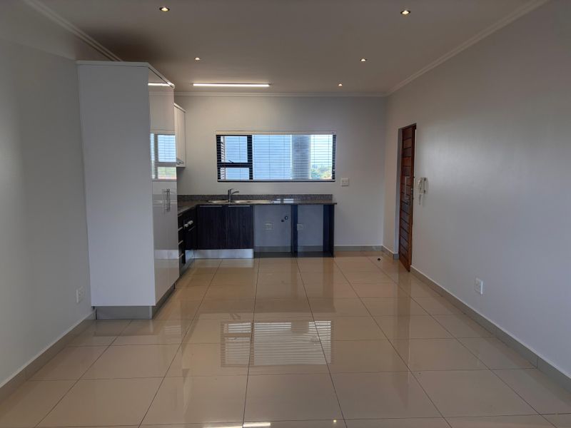 Open-plan kitchen featuring modern cabinetry, granite countertops, stainless steel sink, and tiled flooring, seamlessly integrated into the living area.
