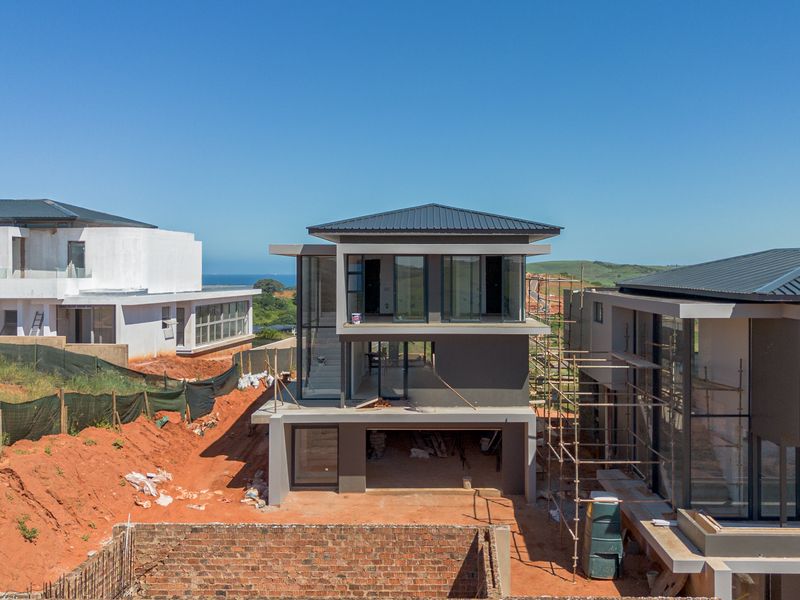 Aerial view of a modern multi-level residential property currently under construction, featuring a metal roof and large glass windows.