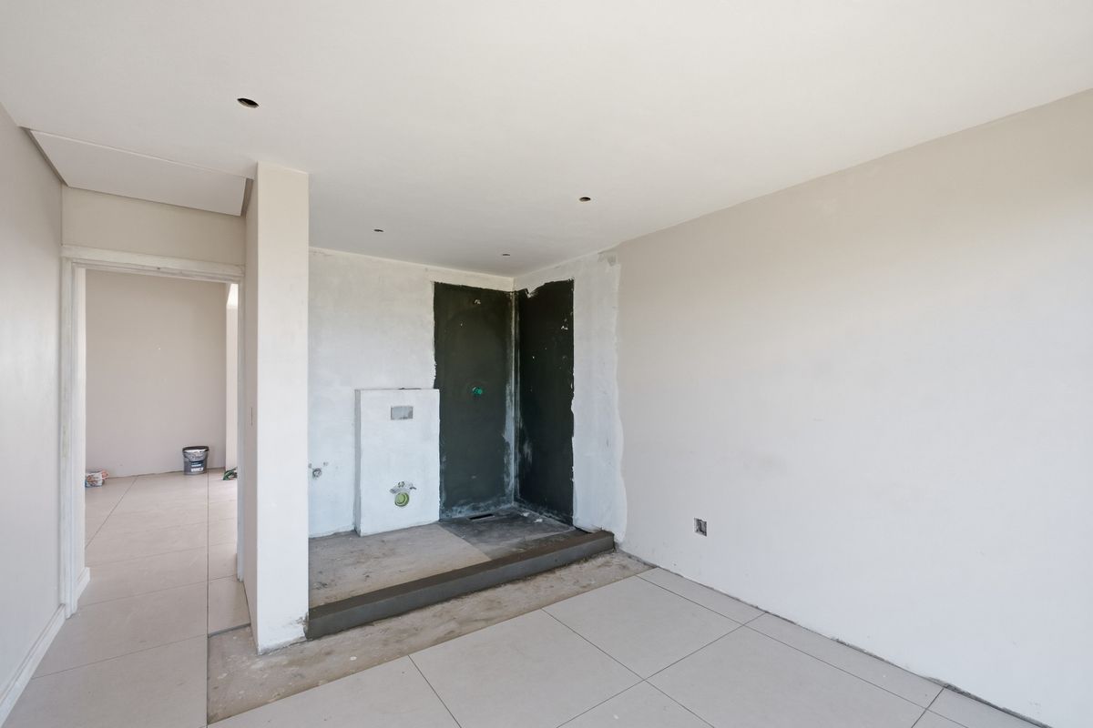 An unfinished bathroom space featuring a walk-in shower area, concealed cistern plumbing, and neutral floor tiling, currently undergoing renovation.