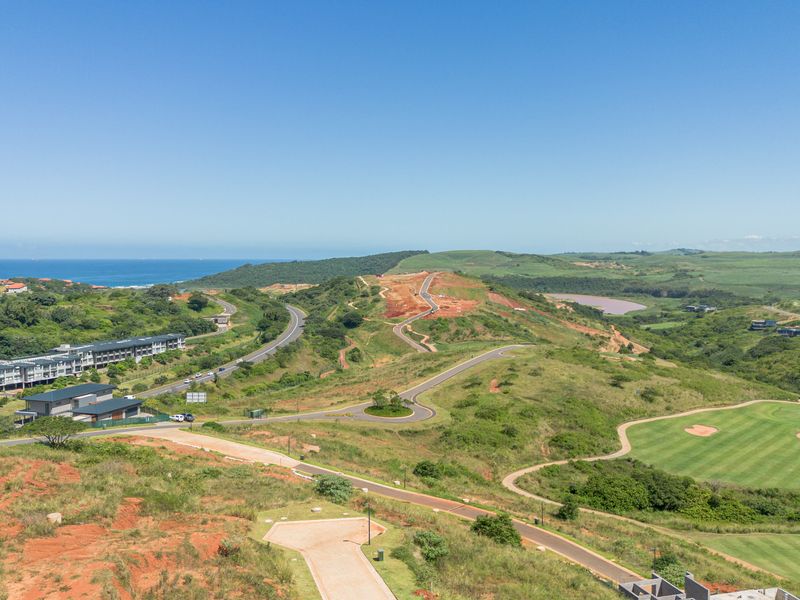 An aerial view of the surrounding estate, featuring paved roads, a golf course, and scenic coastal landscape.